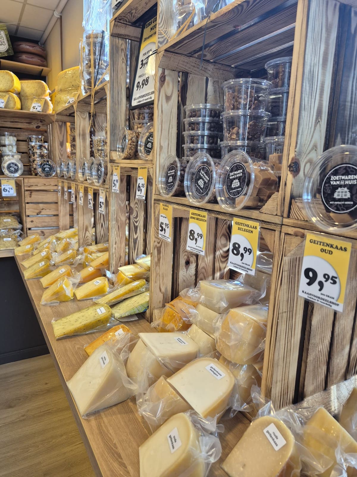 Versgesneden stukken kaas en vers gebrande nootjes in de toonbank van Kaasvoordeelshop Burgum