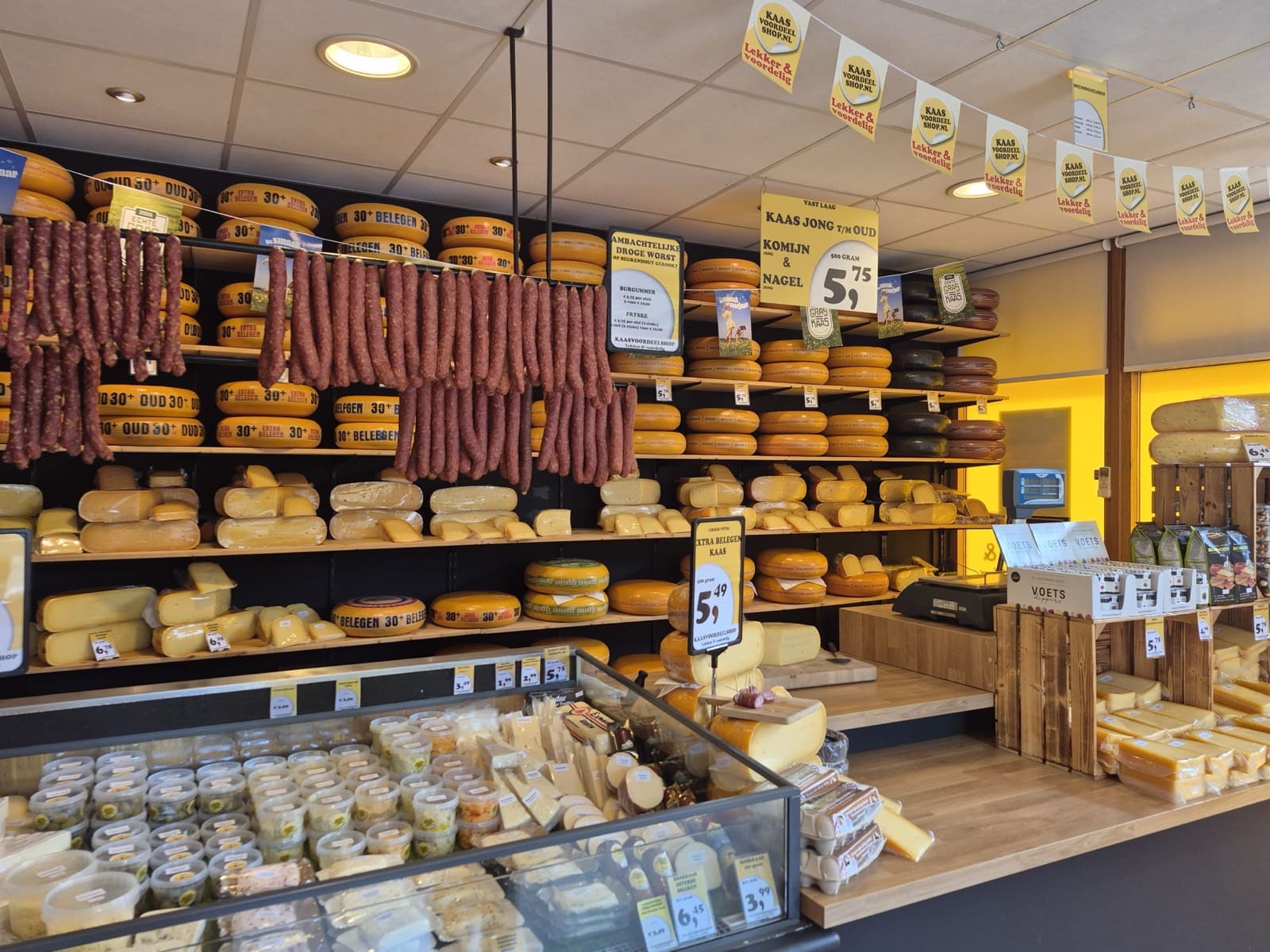 Kaaswand en toonbank van Kaasvoordeelshop Burgum, met ambachtelijke droge worst en verse kaas